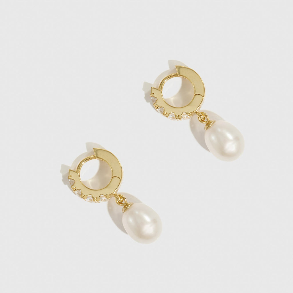 Gold hoop earrings with pearl drops on a white background