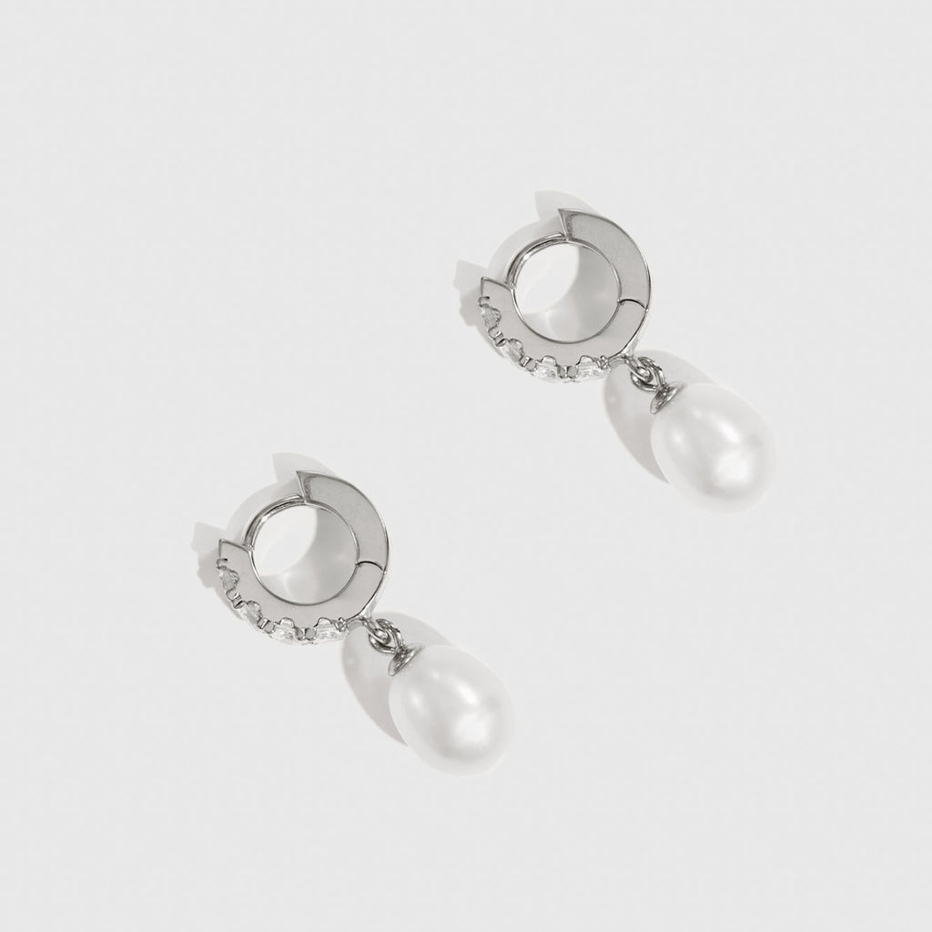 Pair of silver earrings with pearl drops on a white background