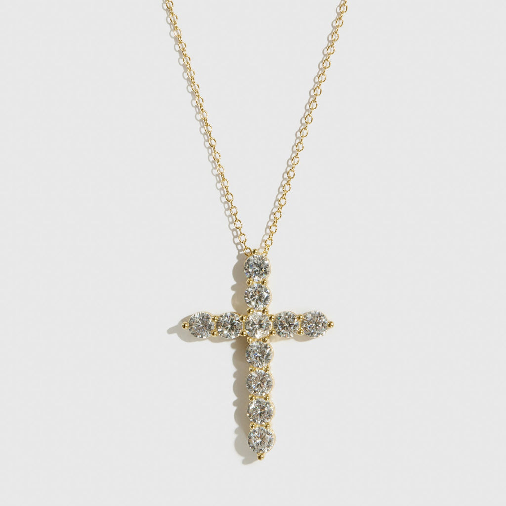 Gold cross necklace with clear stones on a white background